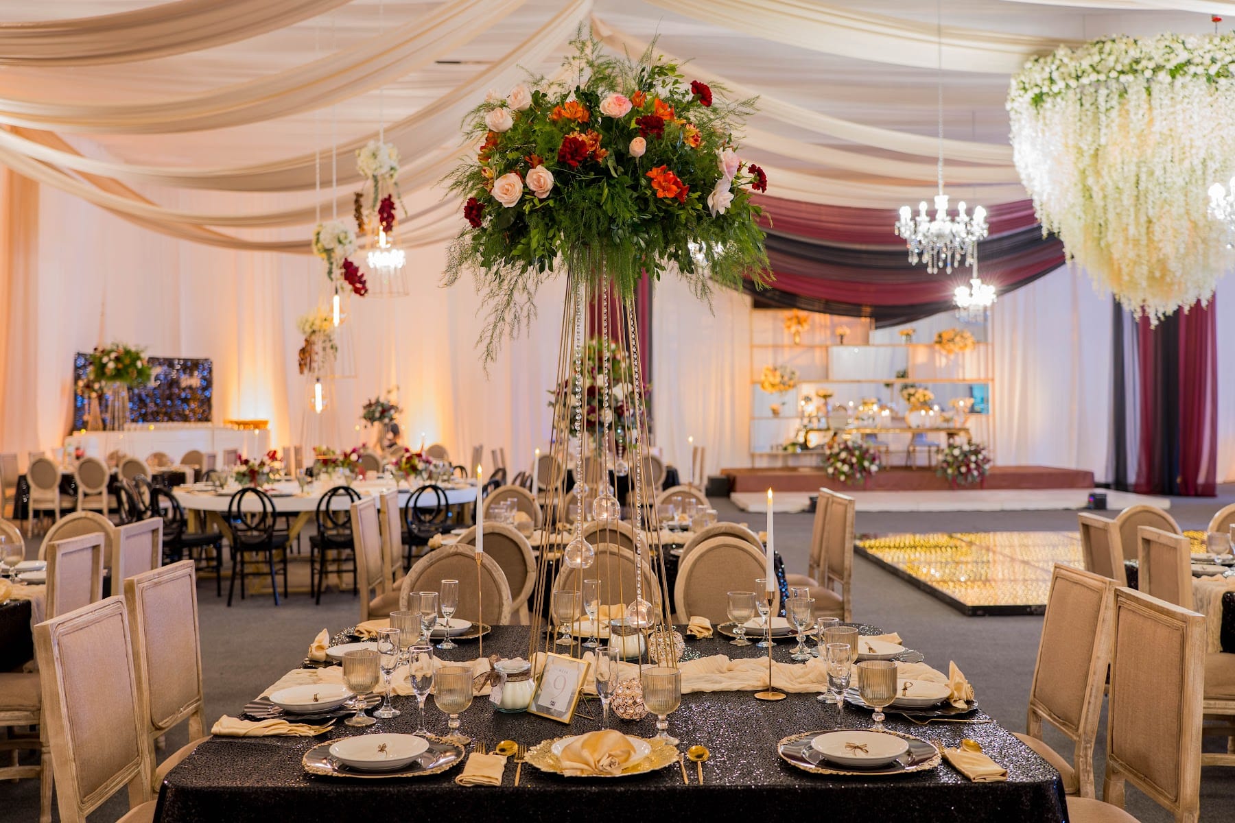 Centro de mesa alto de rosas rojas y blancas bajo candelabro de cristal