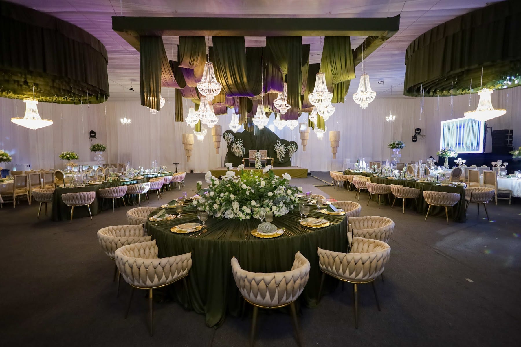 Mesa de novios con respaldo de terciopelo verde y camino de flores blancas