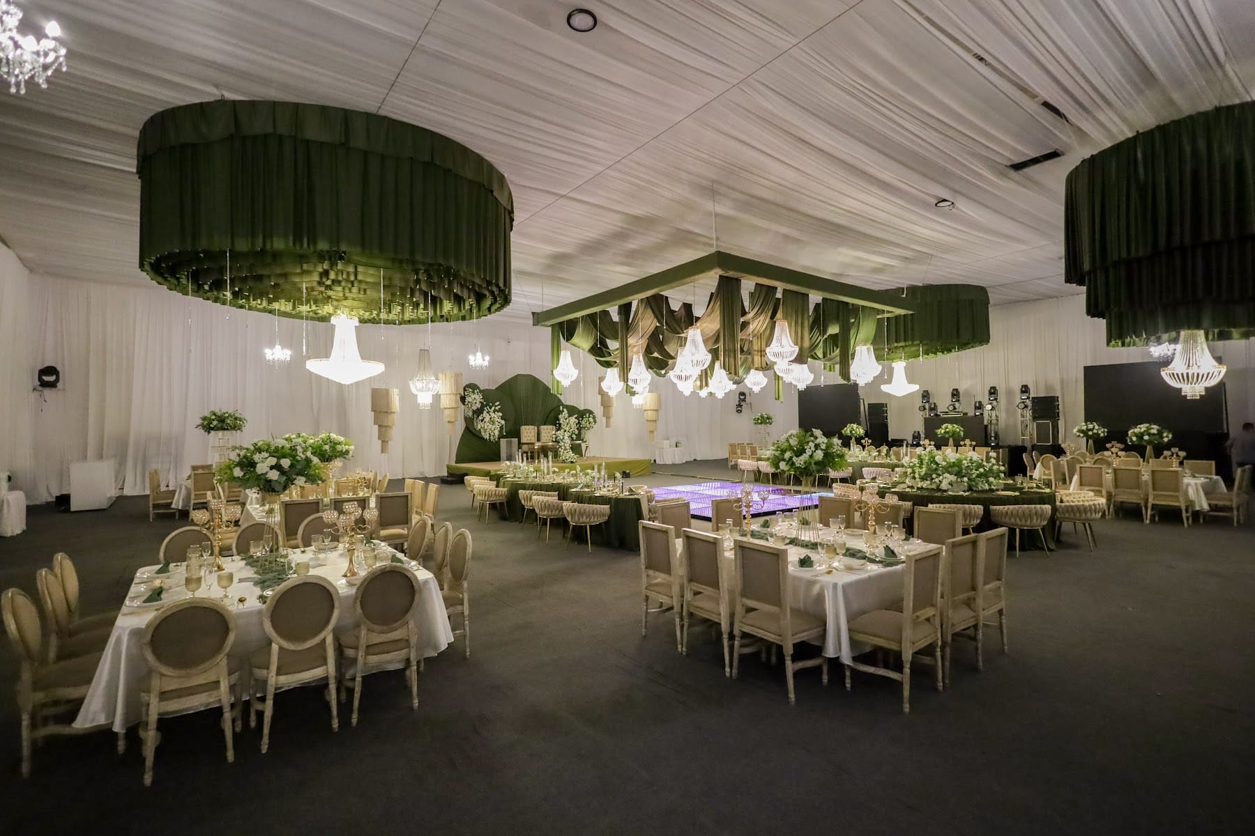 Salón de la boda de Montse y Francisco con entelado blanco, candiles de cristal y mesas con arreglos de flores blancas