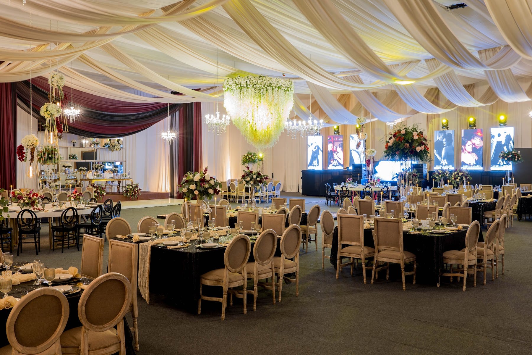 Salón montado para boda con mesas redondas, candelabros y cortinas de seda