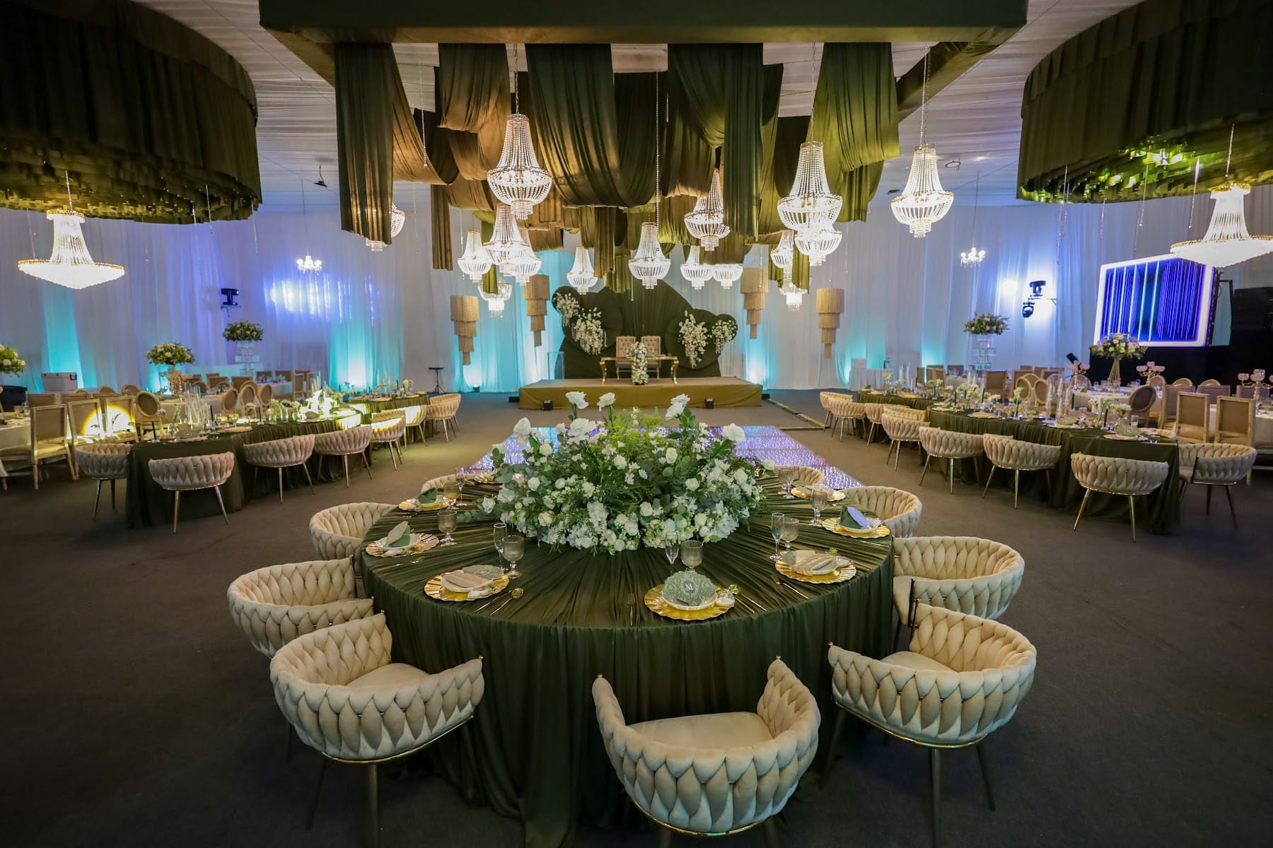 Salón de boda con lámparas de terciopelo verde y mesas con centros de flores