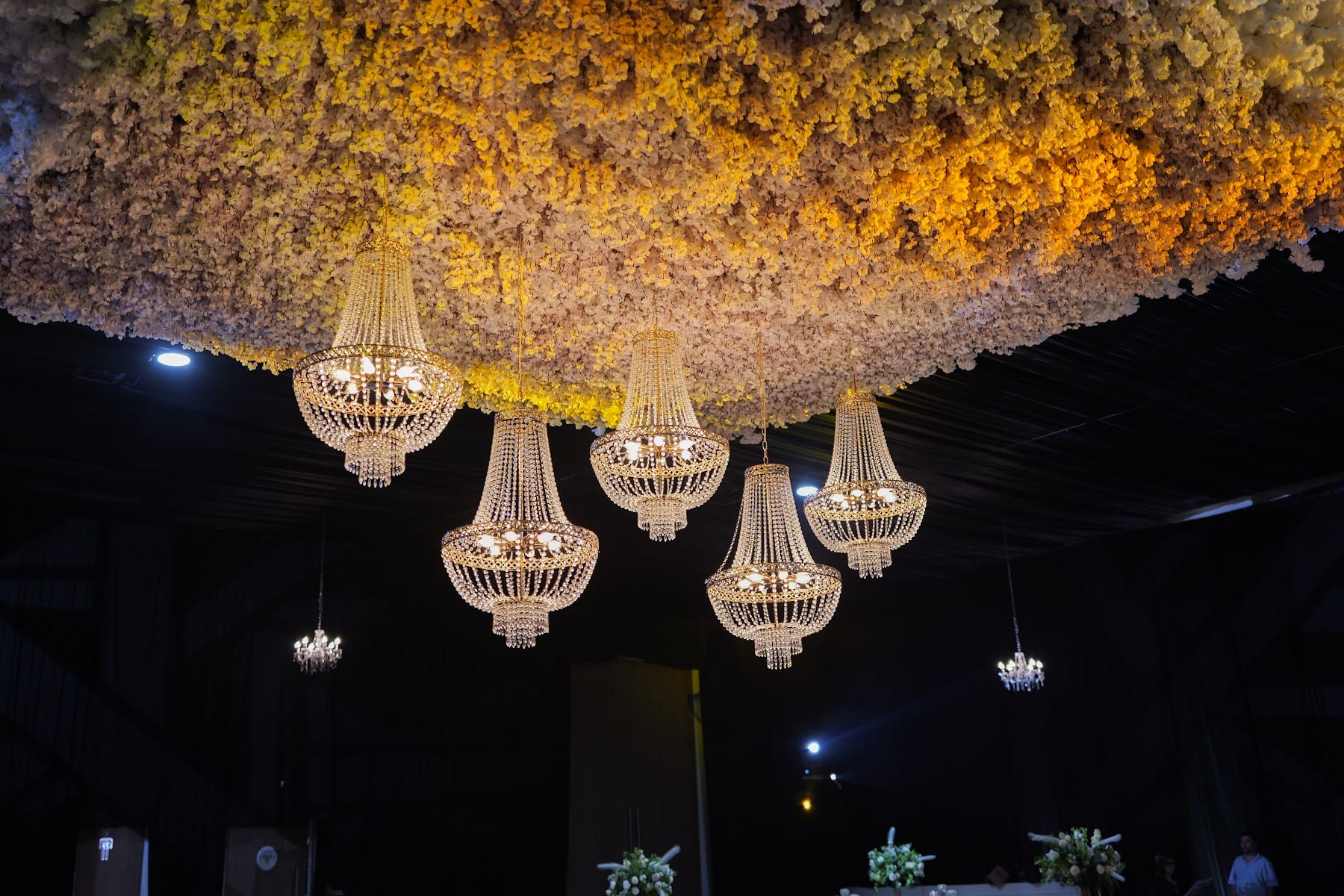 Techo floral dorado con candelabros de cristal sobre el salón de boda