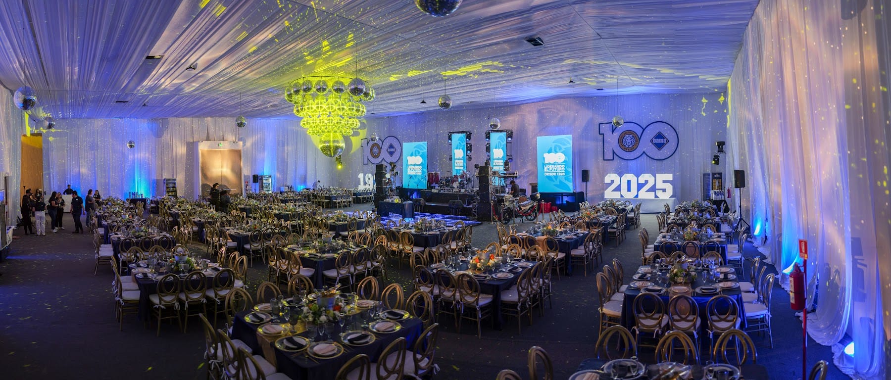 Evento corporativo de aniversario con pantallas, escenario y mesas de gala