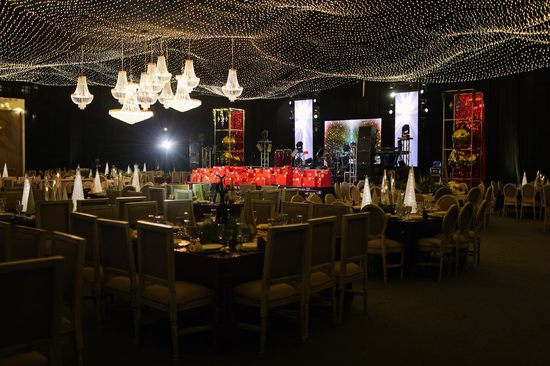 Cena de gala corporativa con escenario iluminado y mesas montadas
