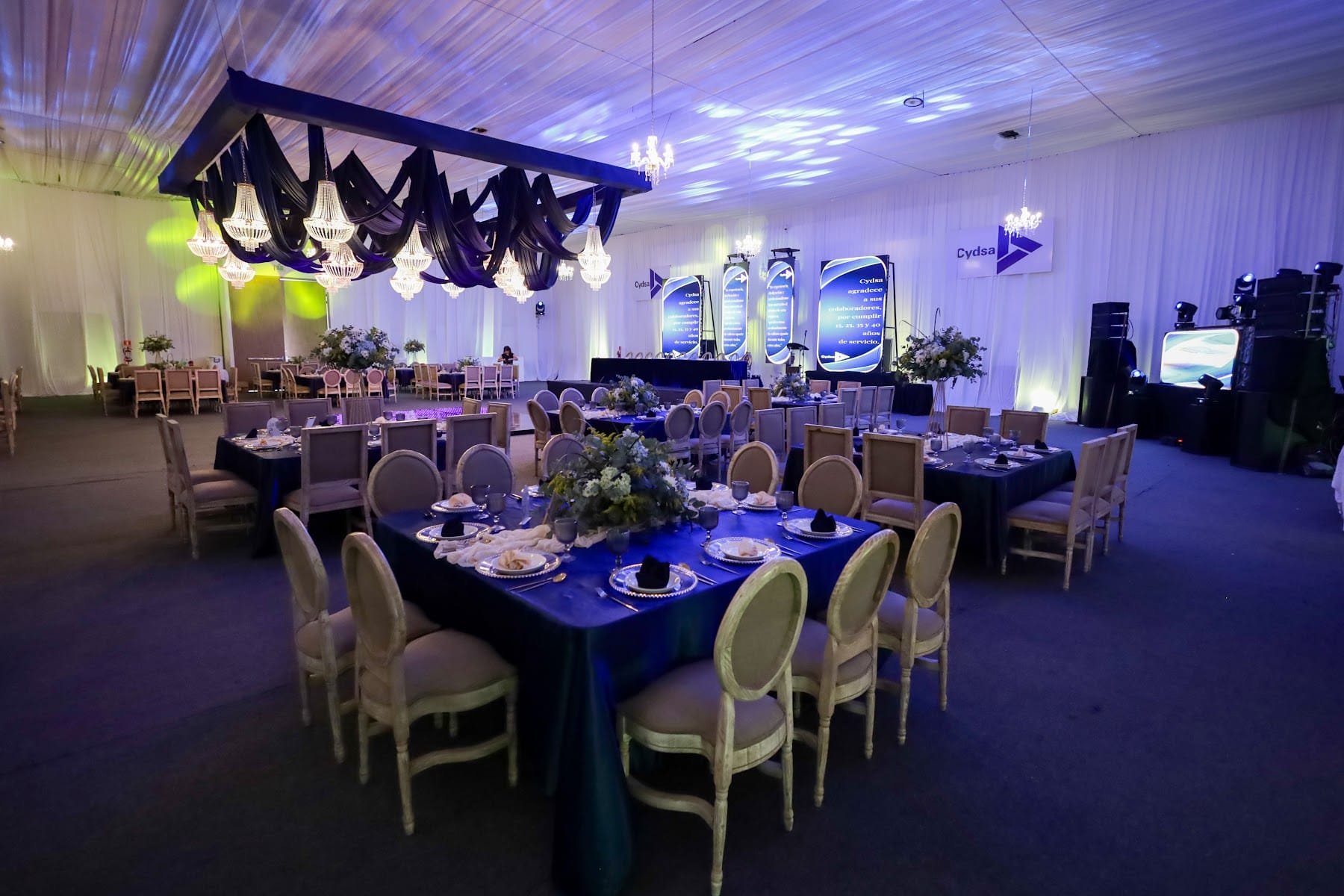 Montaje de banquete corporativo con mesas azules y candelabros