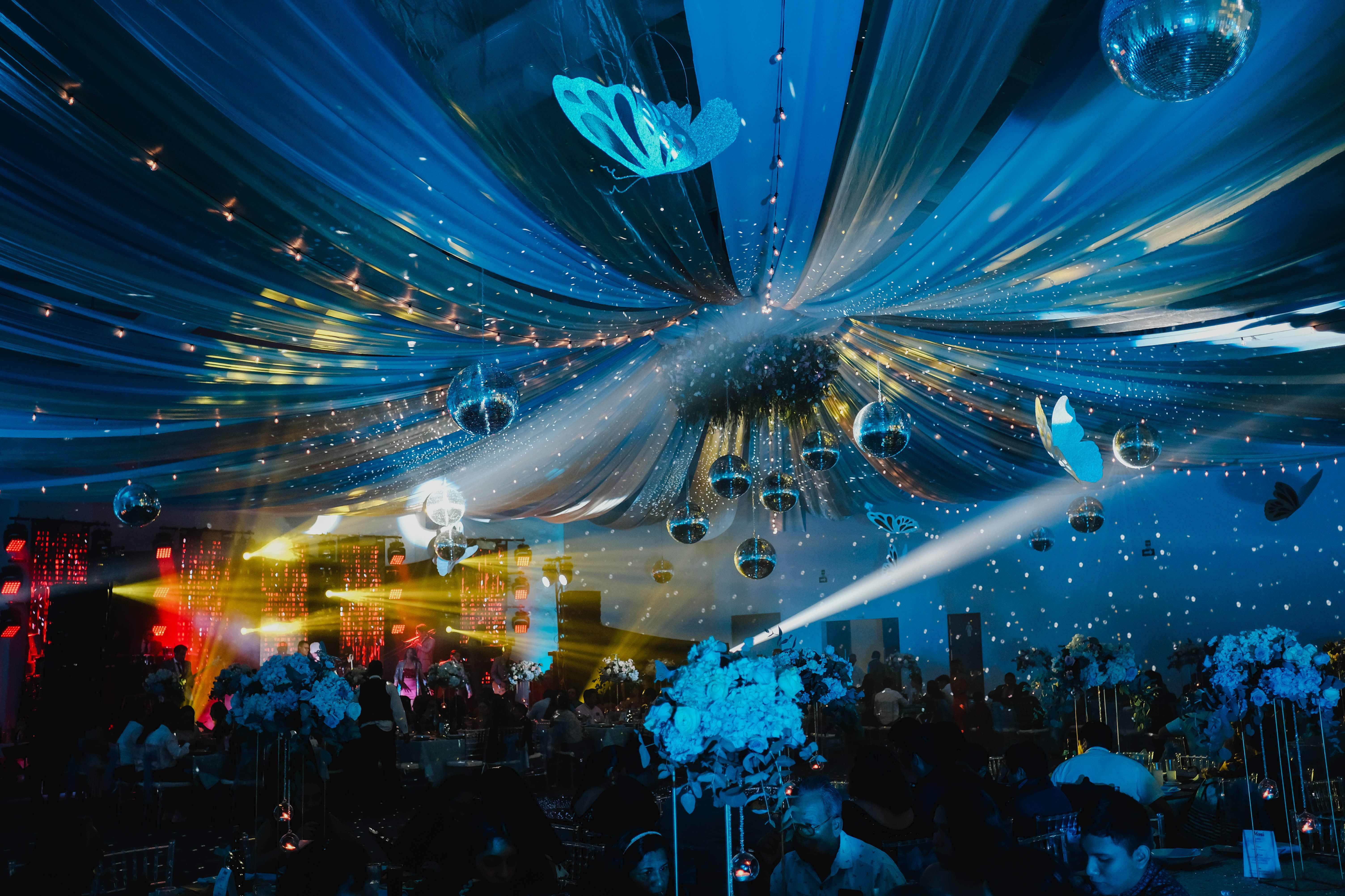 Techo de telas azules con mariposas, esferas de espejo y música en vivo con luces escénicas