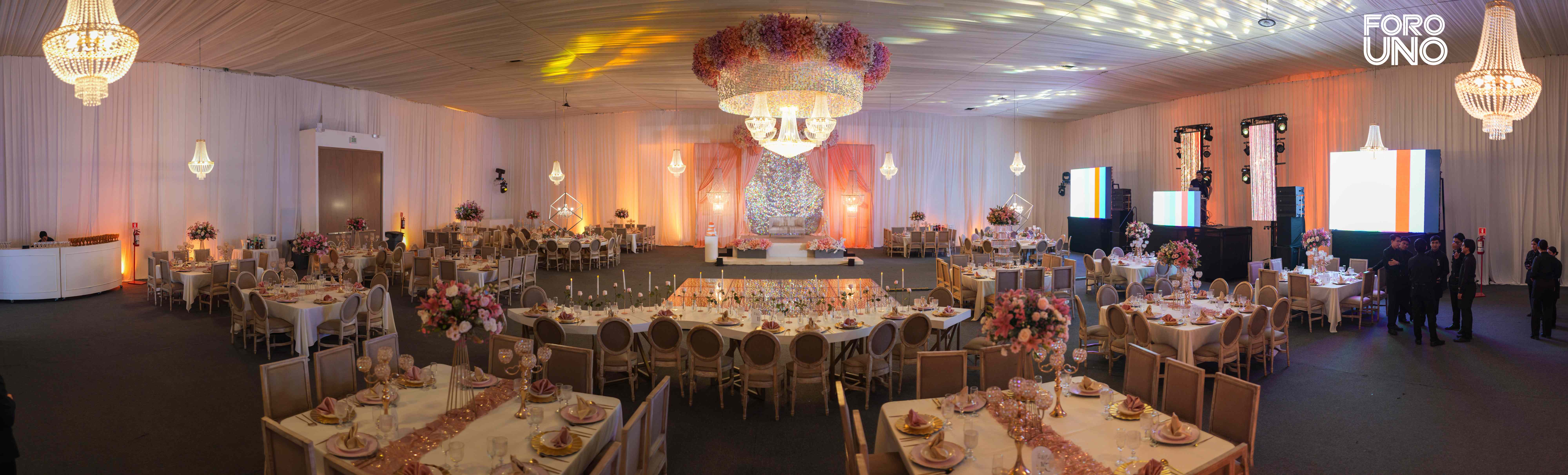 Vista panorámica del salón montado en tonos rosa y marfil con candelabro floral central