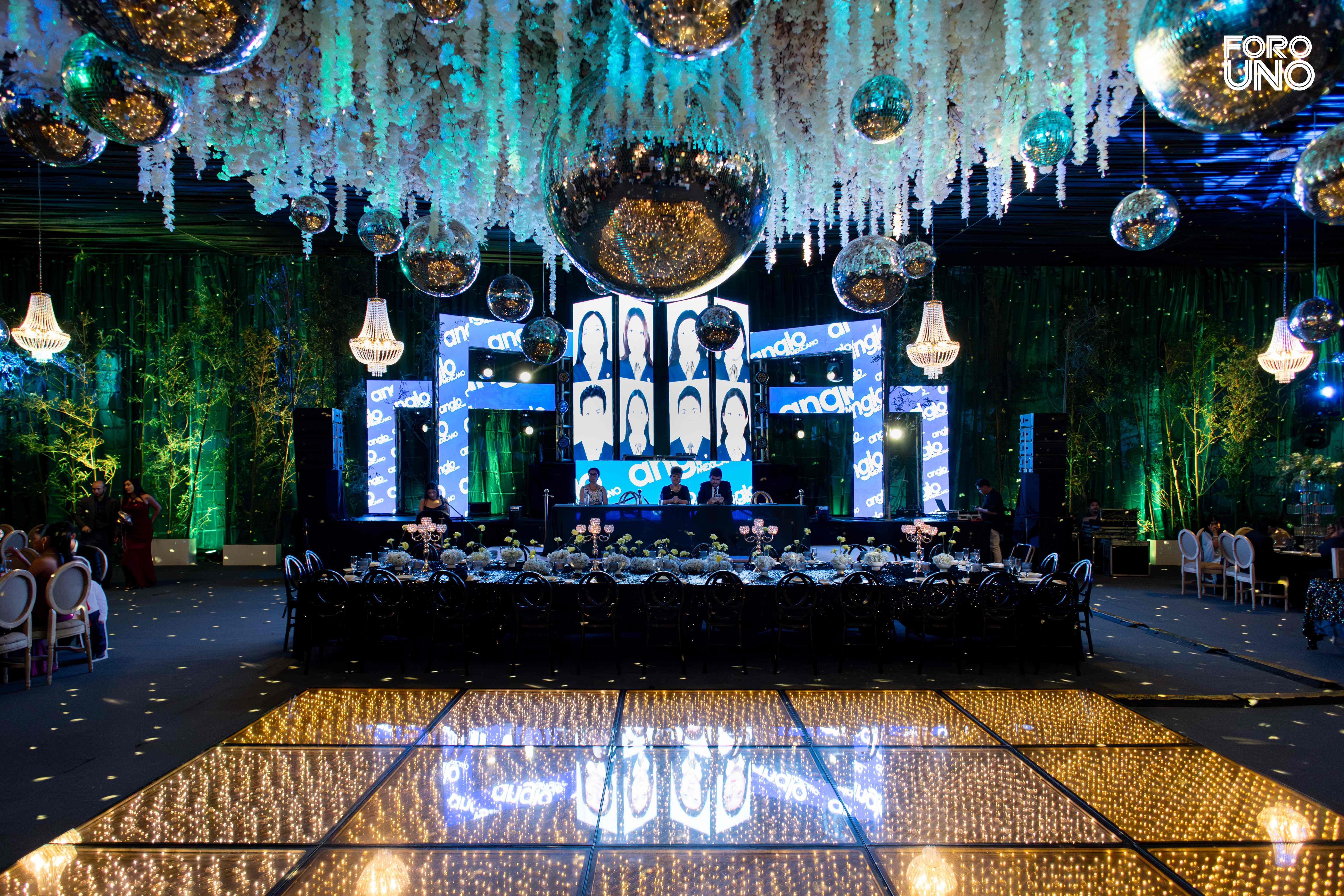 Pista de baile iluminada frente al escenario y techo de flores colgantes