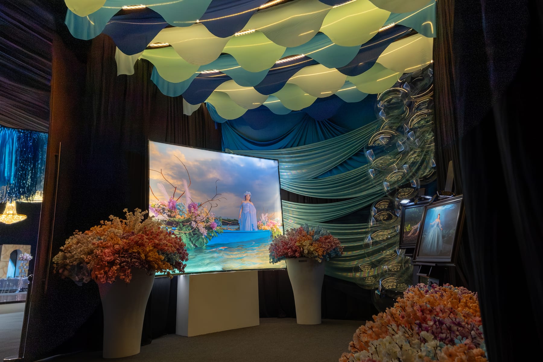 Escenario con olas de tela, pantalla y arreglos de flores coral
