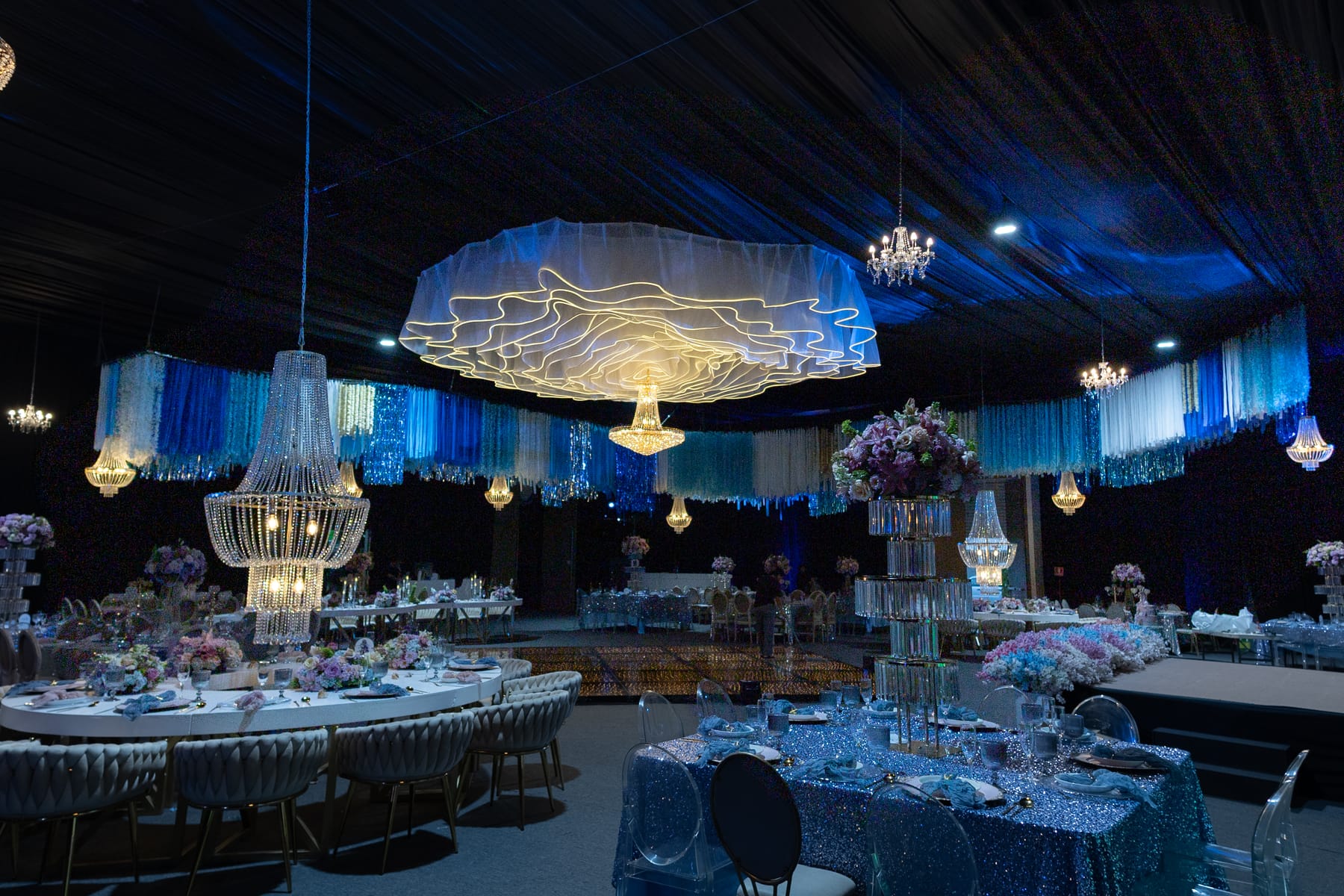 Salón con temática de océano, escultura de olas, candiles y mesas en tonos azules