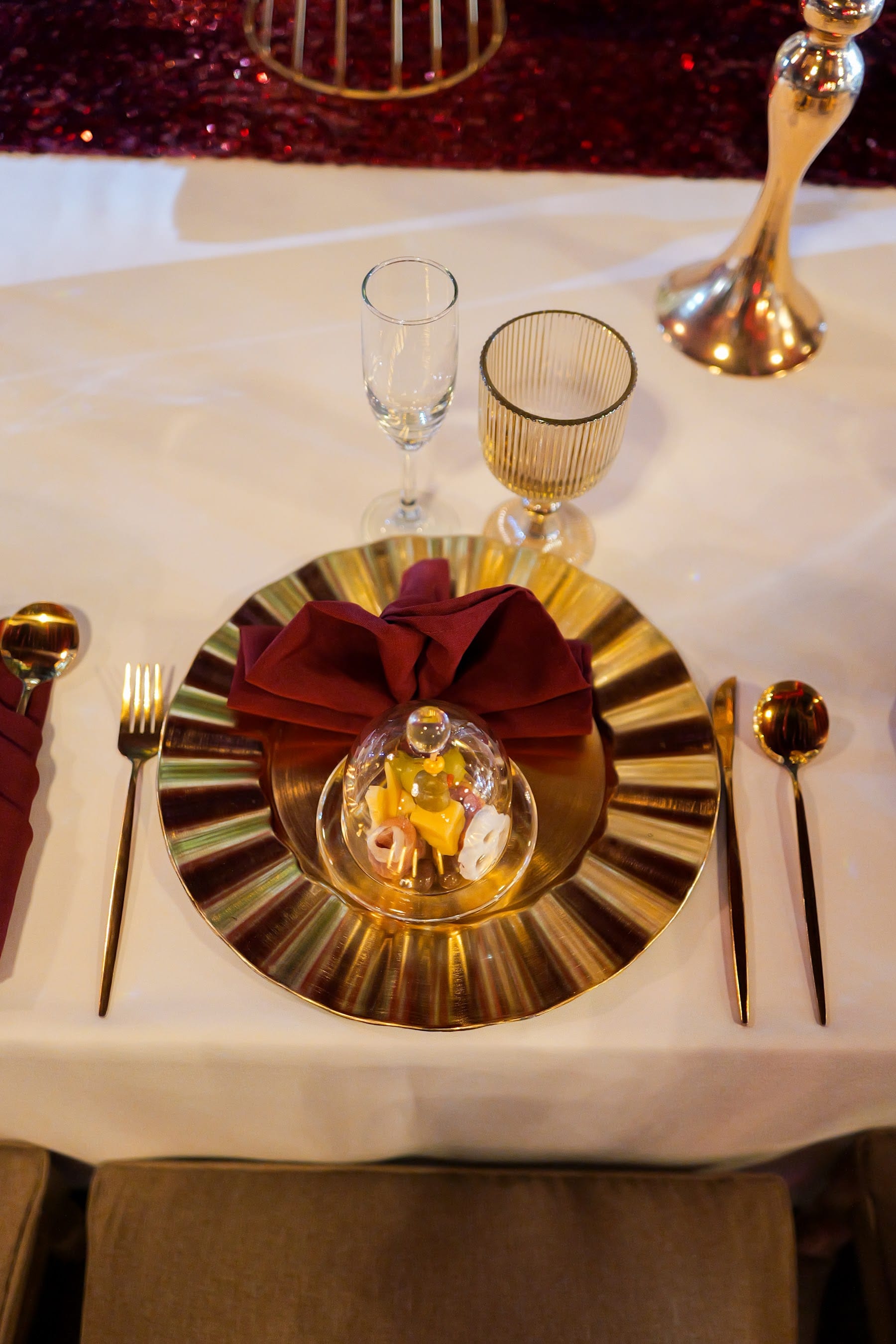 Detalle de plato dorado con servilleta roja y campana de cristal