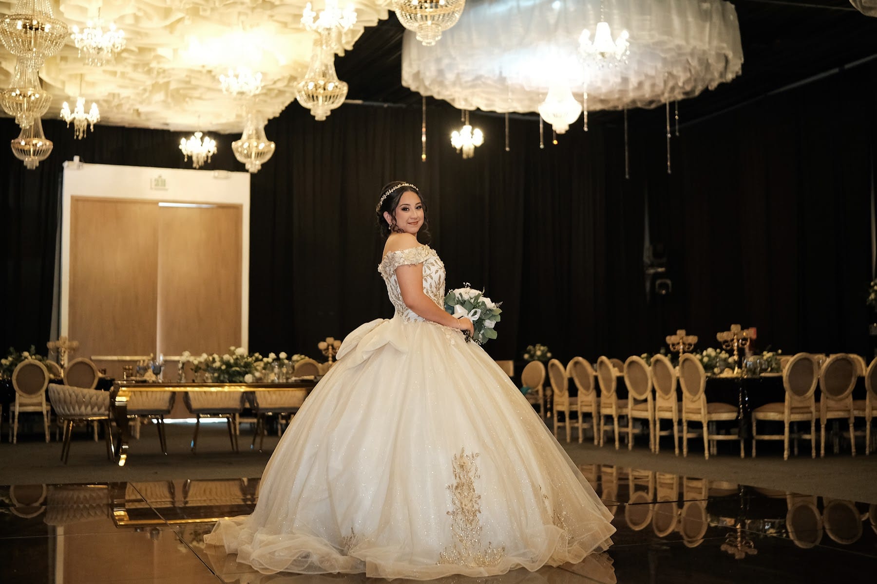 Quinceañera con vestido blanco bajo un techo de flores y candelabros