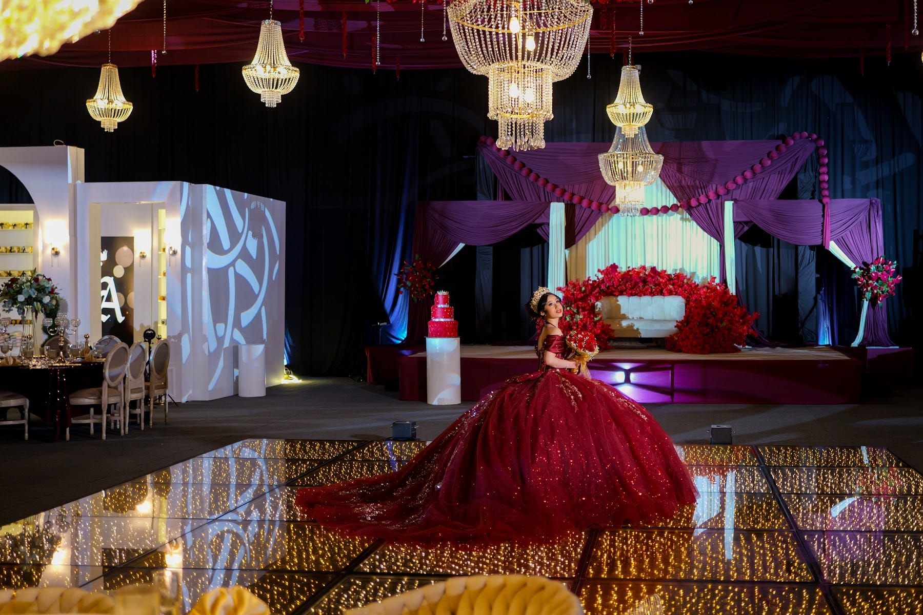 Quinceañera con vestido rojo sobre la pista frente a su escenario temático