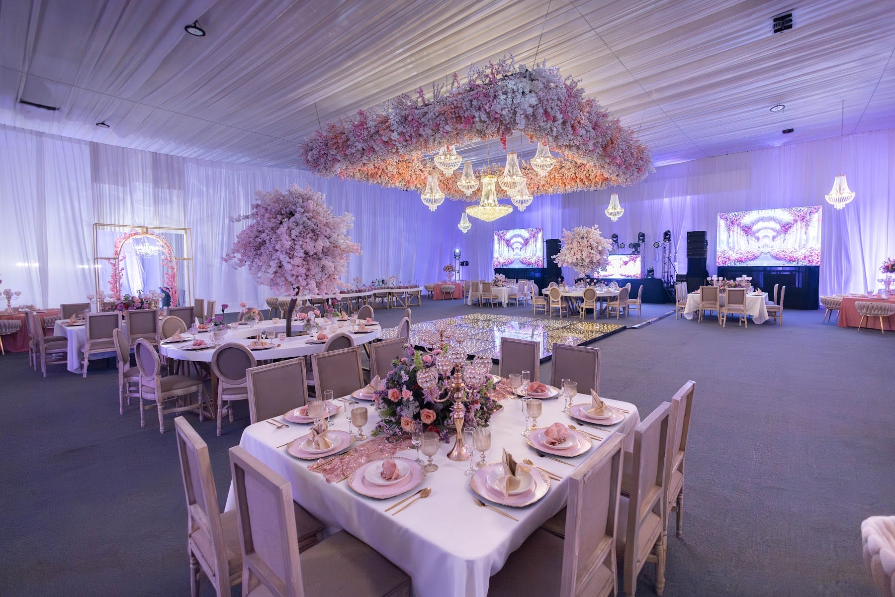 Salón con techo de flores durazno, árboles de cerezo y mesas montadas