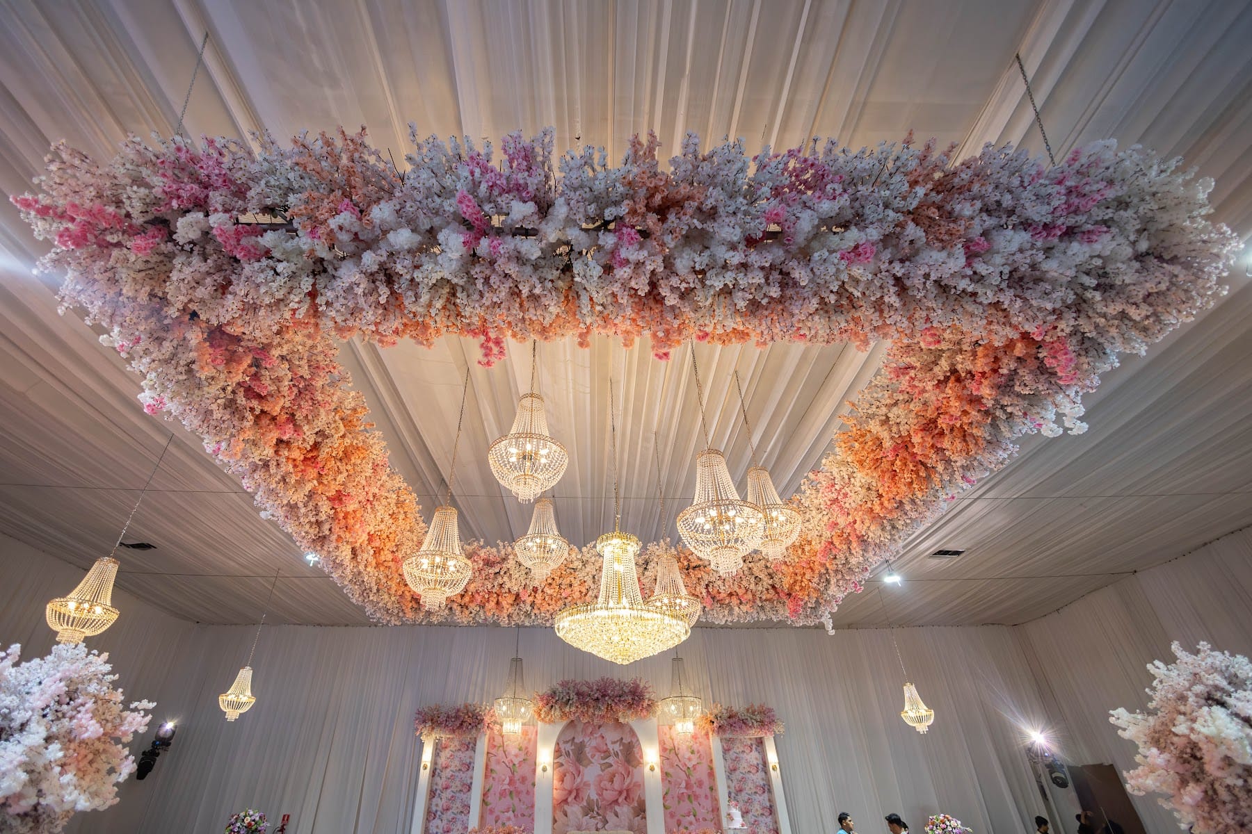 Techo cubierto de flores en tonos rosa y durazno con candelabros